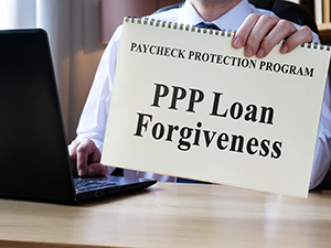 image of man holding sign with text ppp loan forgiveness