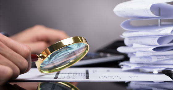 magnifying glass examining papers