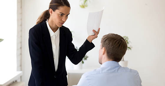 woman in a suit yelling at man in blue shirt