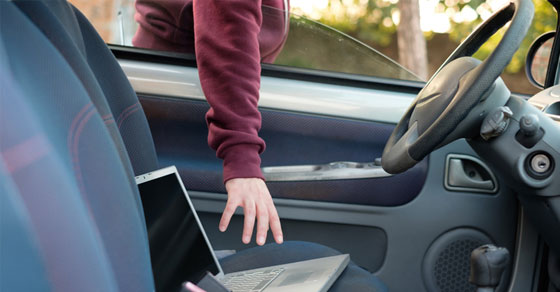 person reaching for laptop through car window