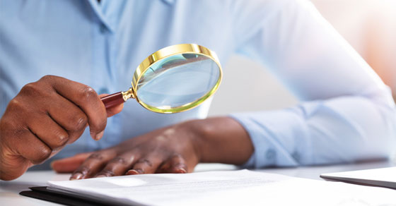person looking at paper with magnifying glass