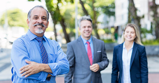 two men and a woman standing outside in suits