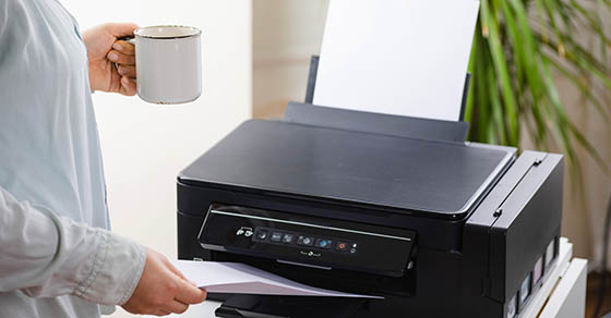 man with cup of coffee by printer