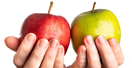 person holding one red and one green apple