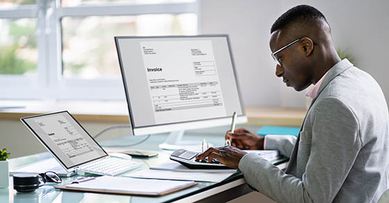 black man working on calculator, laptop, and computer