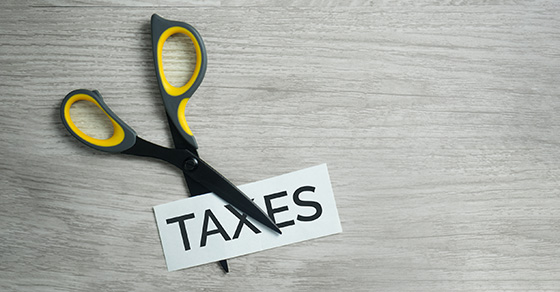black and yellow scissors cutting the word taxes in half