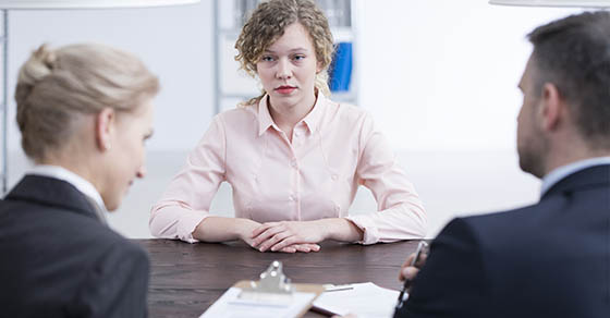 woman in pink shirt, man in black suit, woman in black suit sitting at a table