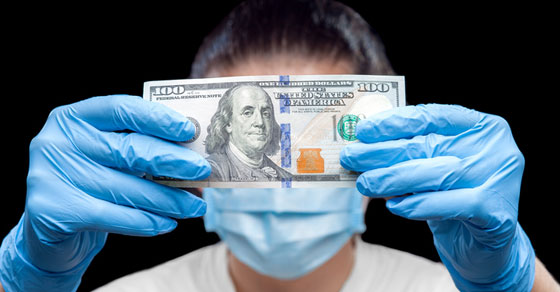 image of man in medical gloves holding dollar bill